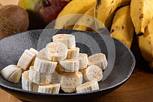 Banana bunch, sliced bananas in bowl and on wooden board