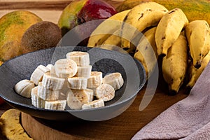 Banana bunch, sliced bananas in bowl and on wooden board