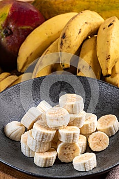 Banana bunch, sliced bananas in bowl and on wooden board