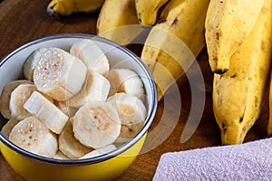 Banana bunch, sliced bananas in bowl and on wooden board