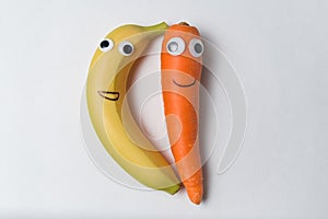 Banana and carrot with the Googly eyes and smiles on white background. Vegetarians concept