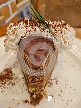 Banana chocolate mille sliced crepes with whipped cream, ground chocolate and rosemary leaves decoration