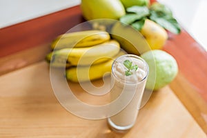 Banana cocktail and fresh bananas on wooden background