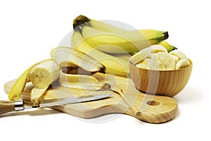 Banana with cut sliced in brown wooden bowl isolated on white background