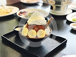 banana ice cream with whipped cream and fresh banana on black plate