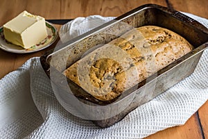 Banana loaf in loaf tin with butter on rustick kitchen table