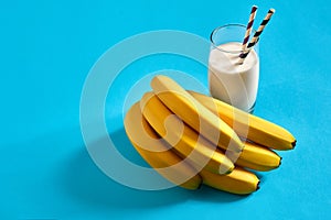 Banana milk drink and a bunch of bananas on a blue background