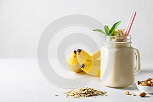 Banana milkshake in mason jar on white board. Vertical format