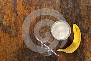 Banana milkshake in plastic cup on wooden background