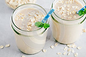 Banana oats smoothie or milkshake in glass mason jars on a stone background