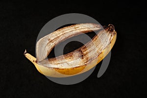 Banana peel on a black background. One over-ripe banana close-up