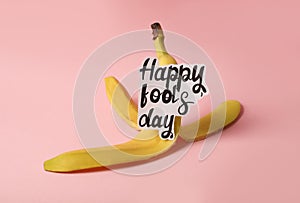 Banana peel with words Happy Fool`s Day on pink background