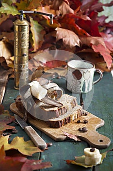 Banana pie on a background of autumn bright leaves, a copper coffee grinder