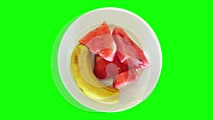 Banana and sliced watermelon on a rotating plate. Rotating fruit plate, top view