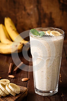 Banana smoothie in tall glass on wooden background