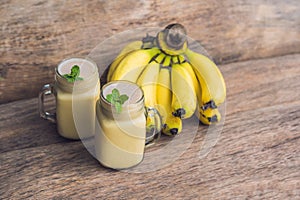 Banana smoothies and bananas on an old wooden background