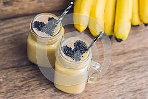 Banana smoothies and bananas on an old wooden background