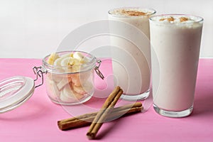 Banana smothie or milkshake with cinnamon on pink  background photo