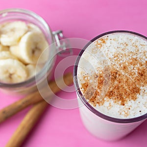 Banana smothie or milkshake with cinnamon on pink  background photo