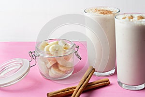 Banana smothie or milkshake with cinnamon on pink  background photo