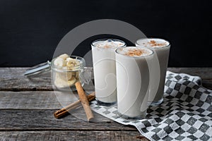 Banana smothie or milkshake with cinnamon on wood background