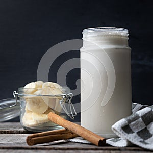 Banana smothie or milkshake with cinnamon on wood background