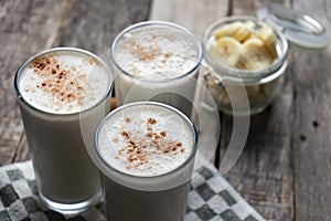 Banana smothie or milkshake with cinnamon on wood background