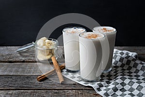Banana smothie or milkshake with cinnamon on wood background photo