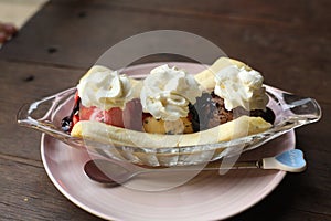 Banana split ice cream dessert in saucer with chokolate icing and cream
