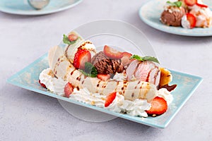 Banana split ice cream with syrup and strawberry on blue plate, top view