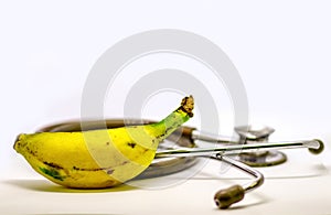 Banana and stethoscope isolated in white background as doctor recommendation health and nutrition purpose with room for text. Medi