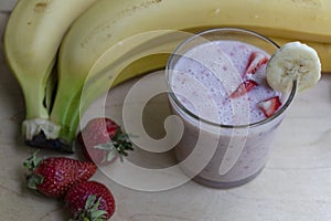 Banana Strawberry Milkshake. Glass cup on a wooden background. Homemade
