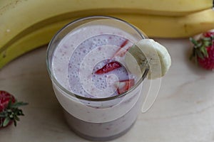 Banana Strawberry Milkshake. Glass cup on a wooden background. Homemade