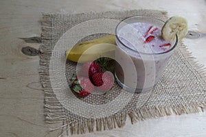 Banana Strawberry Milkshake. Glass cup on a wooden background. Homemade