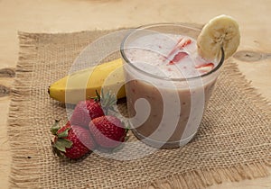 Banana Strawberry Milkshake. Glass cup on a wooden background. Homemade