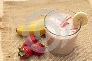 Banana Strawberry Milkshake. Glass cup on a wooden background. Homemade