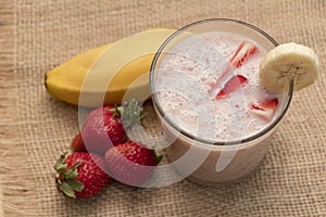 Banana Strawberry Milkshake. Glass cup on a wooden background. Homemade