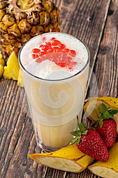 Banana, strawberry and pineapple smoothie on wooden table and bubble tea or boba tea balls on it