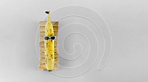 Banana with sunglasses relaxing on the wooden beach bed. Summer vacation concept