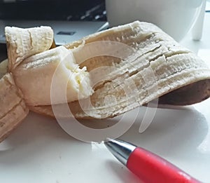 Banana on table with computer and red pen