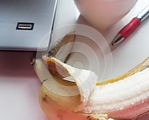 Banana on table with computer and red pen