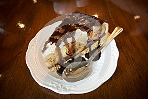 Banana Vanilla Cake with Chocolate in a white dish placed on a wooden background in a cafe.Selective focus