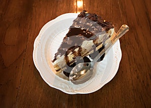 Banana Vanilla Cake with Chocolate in a white dish placed on a wooden background in a cafe.Selective focus