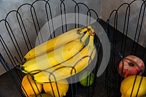 bananas, apples and other fruits in a container on the stove