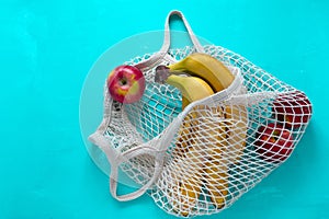 bananas and apples in a trendy string bag on a bright blue background, no plastic bags and healthy lifestyle concept