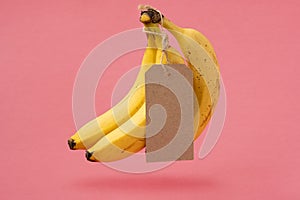 Bananas with a blank tag levitating on a pink background