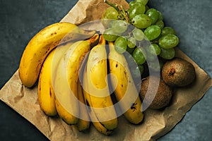 Bananas with bunches of grapes and kiwis