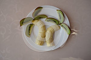 Bananas and kiwi on a white plate. Still life palm tree.