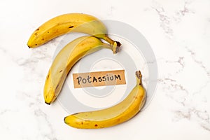 Bananas with a potassium sign on a white and gray marble kitchen counter