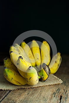 Bananas start to ripen and bruise put on sackcloth on a rustic wooden floor.